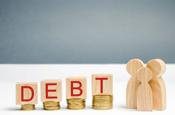 Ð¡oins on the rise, wooden blocks with the word Debt and family. Financial difficulties. There is a growing debt for housing, a house / apartment. Mortgage. High interest rates. Unable to pay off debts