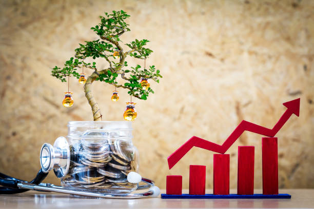 Bottle bank and stethoscope and  tree with growing to gold money bag and red bar graph with up on brown background in the office, Saving money and financial health check or loan to investment concept.