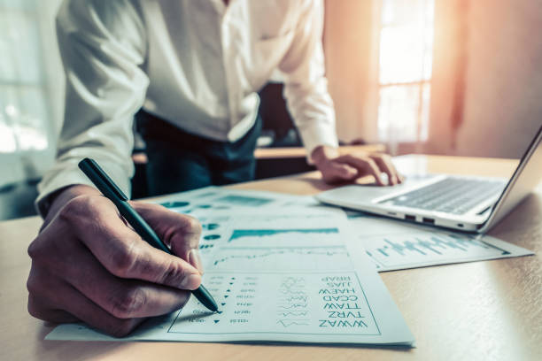 Businessman accountant or financial expert analyze business report graph and finance chart at corporate office. Concept of finance economy, banking business and stock market research.