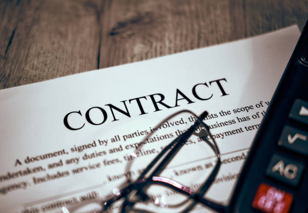 A pen for the signature of the Contract. Glasses and calculator on a black calculator on a wooden table