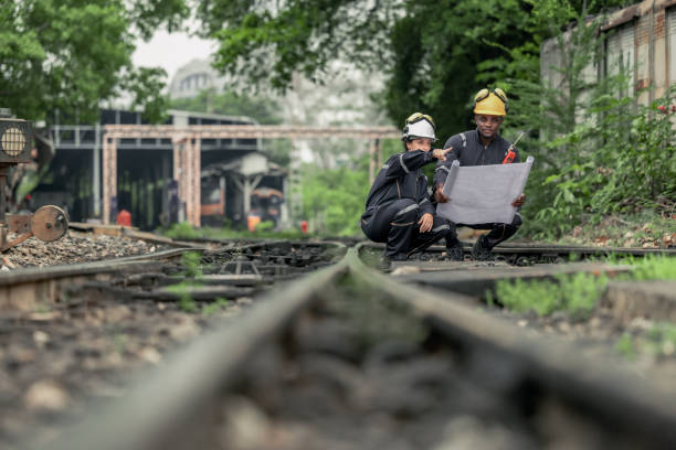 Pi8 Locomotive engineers collaborating and referencing blueprint to guide maintenance task, troubleshoot issues within rial infrastructure and network. Ensuring reliability and safety of train operations